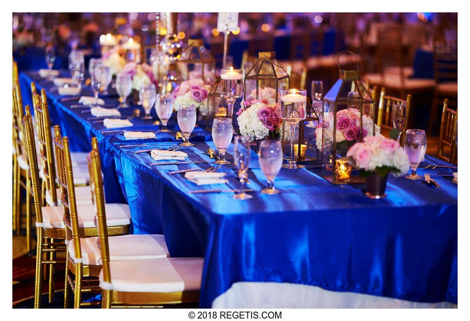 Blue table linens, gold chairs, pink flowers and candlelit lanterns at Vivek and Kinita’s engagement reception.