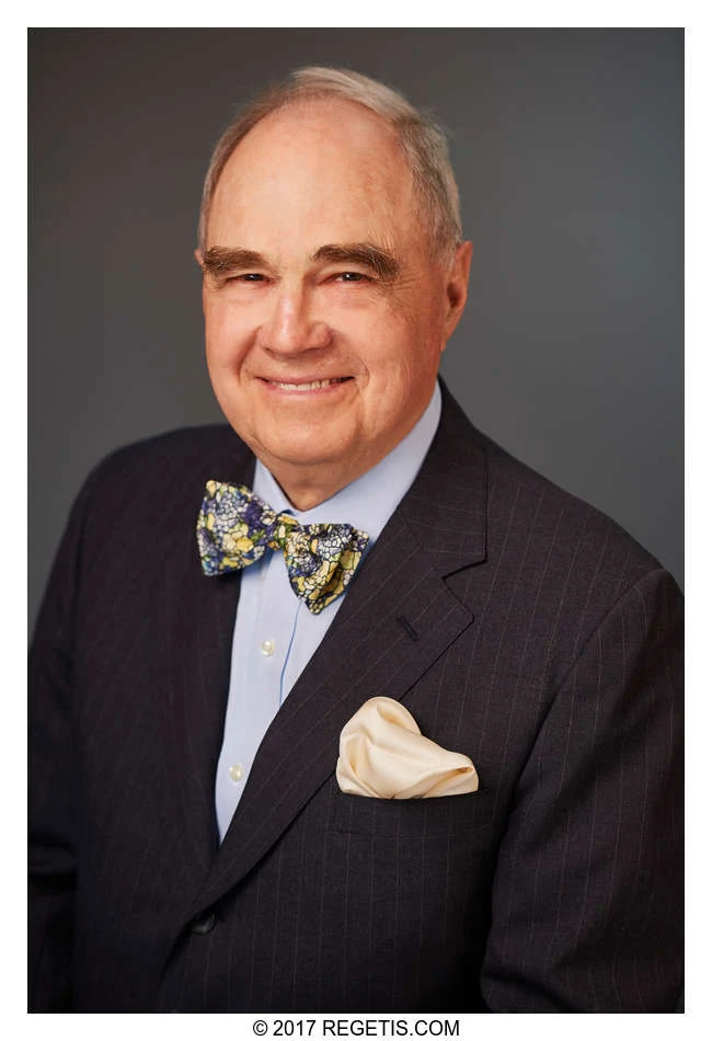 A Walker Jones attorney in a dark suit and patterned bow tie, photographed against a charcoal-gray backdrop by The Regeti’s