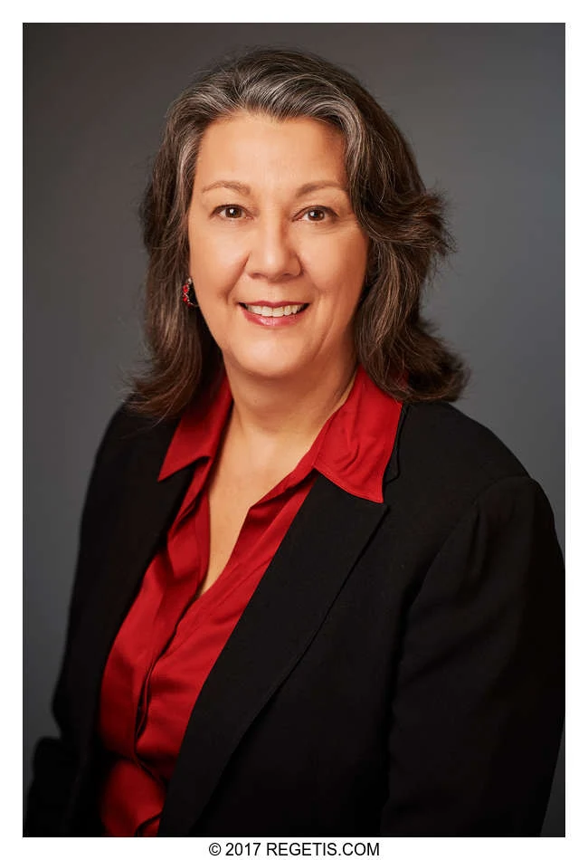 A Walker Jones attorney in a black jacket and red blouse, photographed against a charcoal-gray backdrop by The Regeti’s