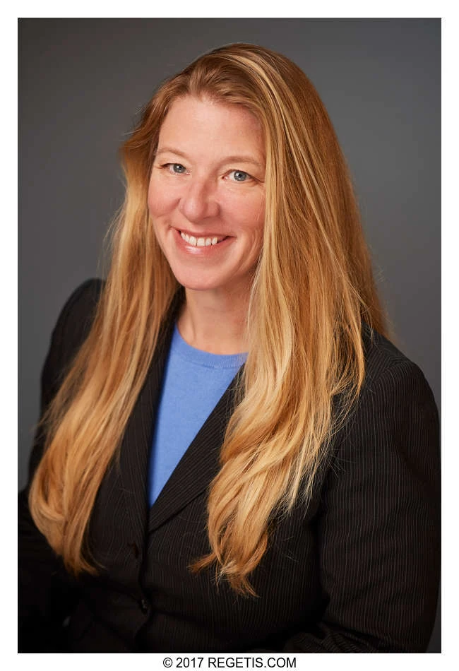 A Walker Jones attorney in a black jacket and blue blouse, photographed against a charcoal-gray backdrop by The Regeti’s