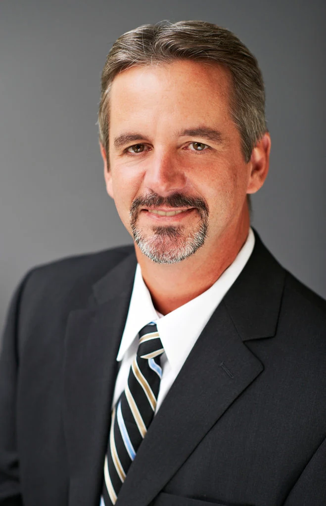 A professional in a dark suit photographed in an office by The Regeti’s