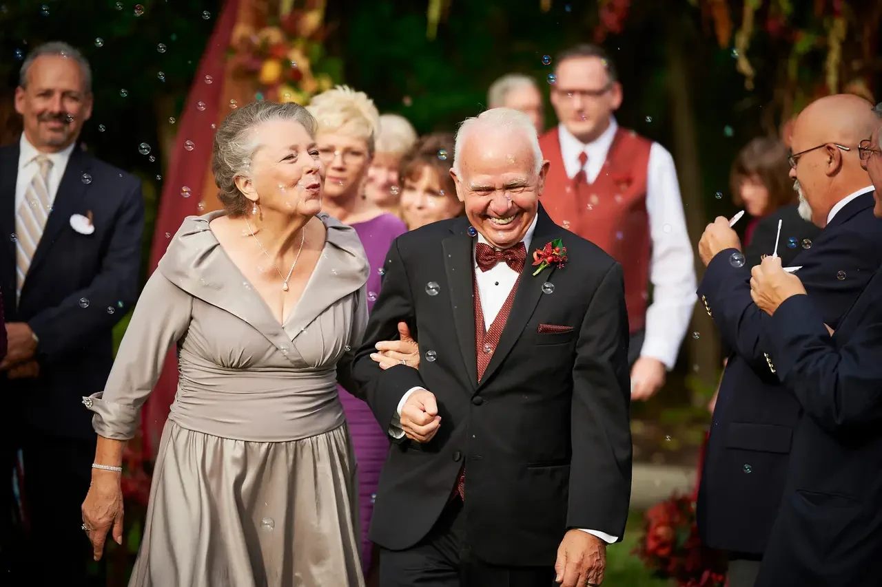 Beverly’s parents walk arm in arm through bubbles during the wedding recessional