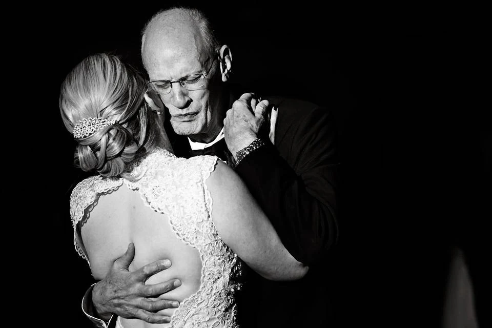 A father holds his daughter close during their dance at Laura and Justin’s wedding, photographed in black and white