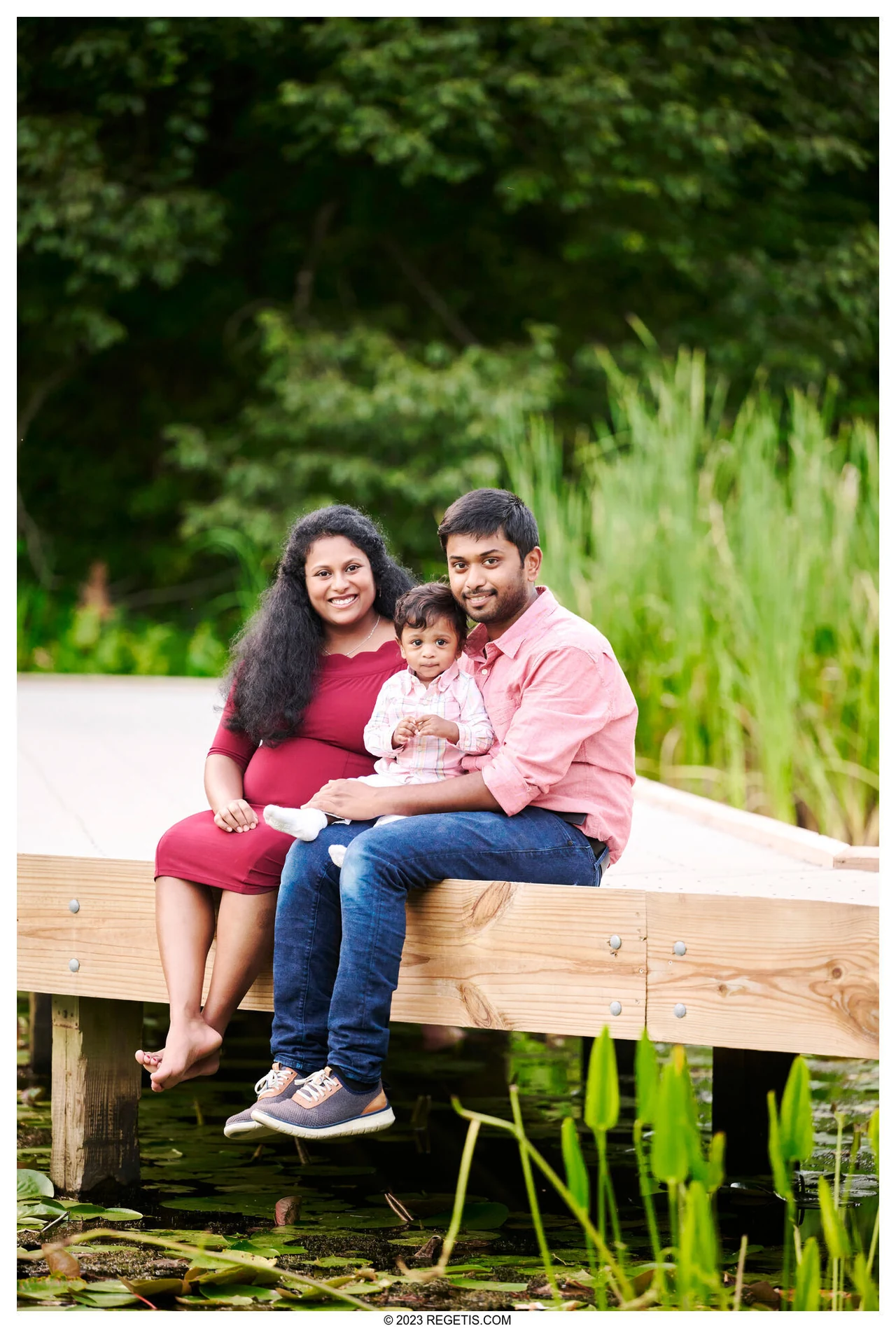 A family of three sitting together beside a pond at Ellanor C. Lawrence Park, photographed by The Regeti’s