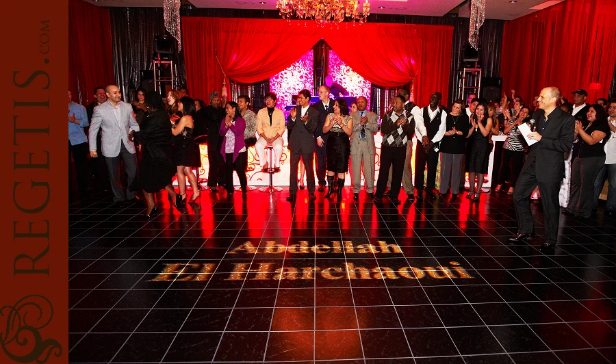 Four Seasons employees celebrating together on a red-lit ballroom dance floor at their holiday party.