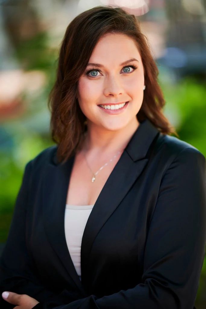 A professional photographed outdoors with soft greenery behind her by The Regeti’s
