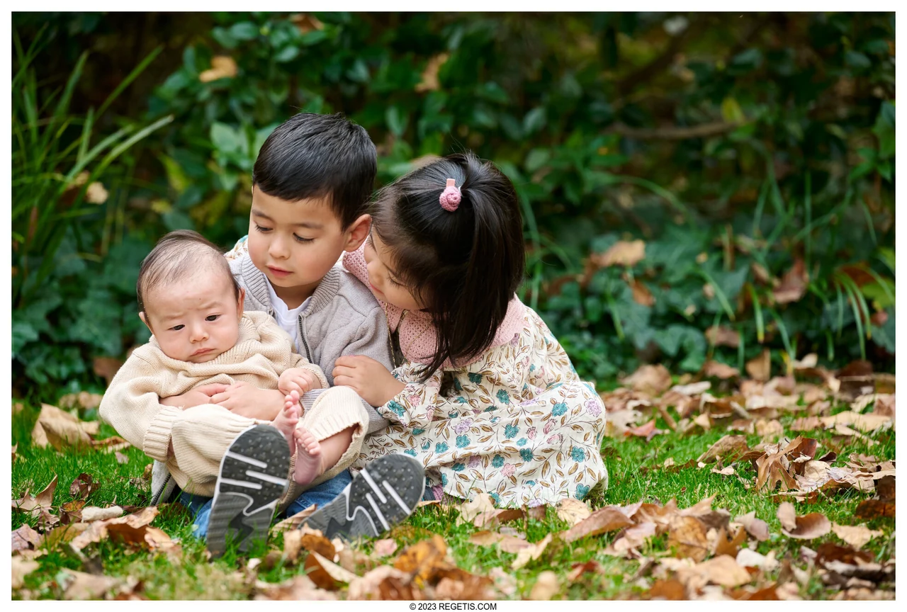 Three children leaning close together among the autumn leaves at McCrillis House and Gardens, photographed by The Regeti’s