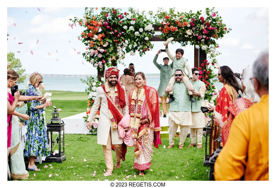 Julia and Tarak walk between celebrating guests after their Hindu ceremony beside the Chesapeake Bay.