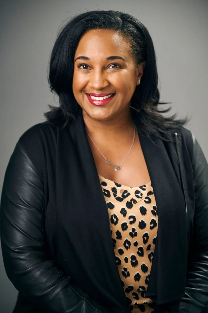 A smiling professional in a black jacket and patterned blouse in a PATH Foundation headshot by The Regeti’s