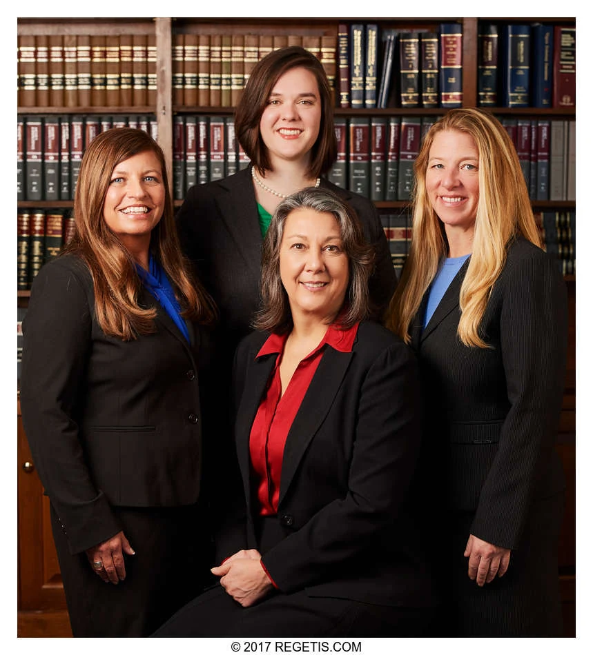 Four Walker Jones attorneys in a color group portrait in front of law-library bookshelves, photographed by The Regeti’s