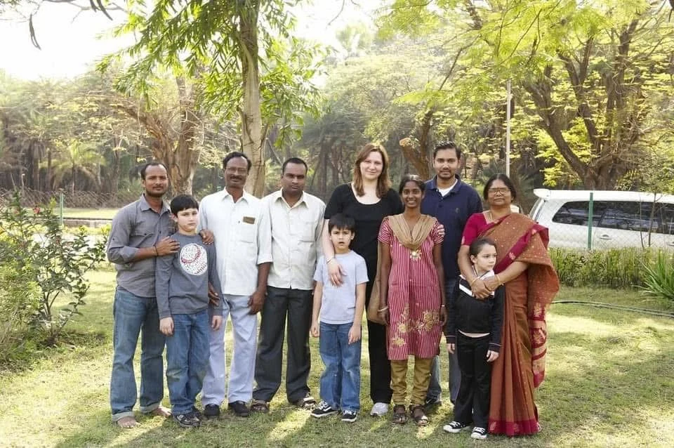Amy and Srinu with their family, gathered outdoors beneath the trees