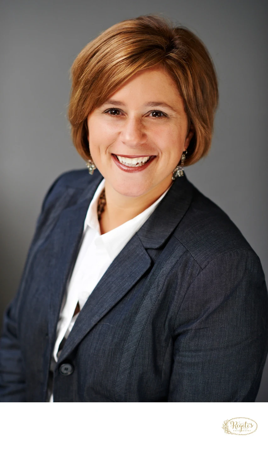 A professional in a navy suit, photographed with natural light at an office in Reston, Virginia, by The Regeti’s