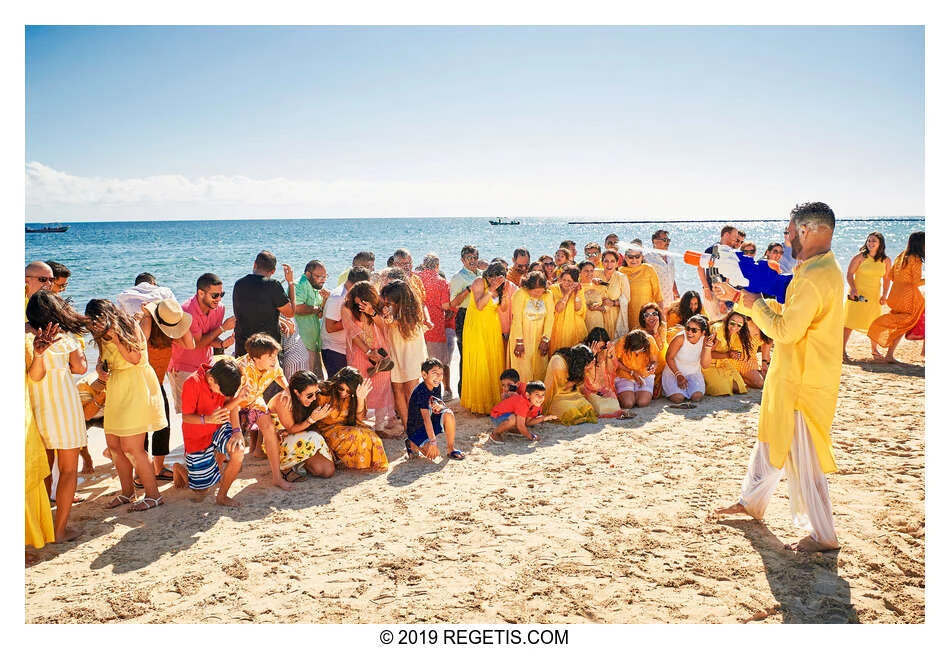 Anuj spraying the laughing wedding guests with a water gun on the beach during his and Shruthi’s haldi celebrations in Cancun