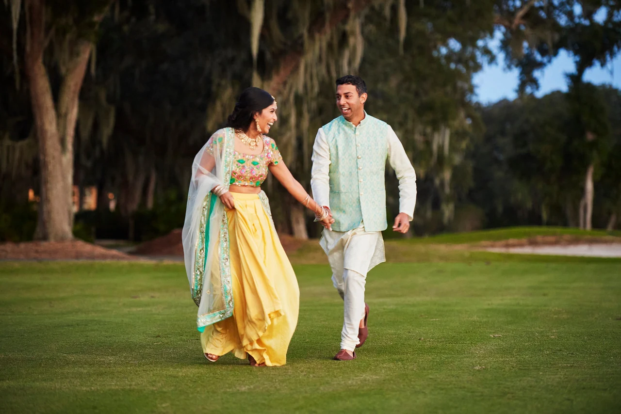 Shruthi and Arjun laughing and moving hand in hand across the lawn during their Amelia Island pre-wedding celebrations