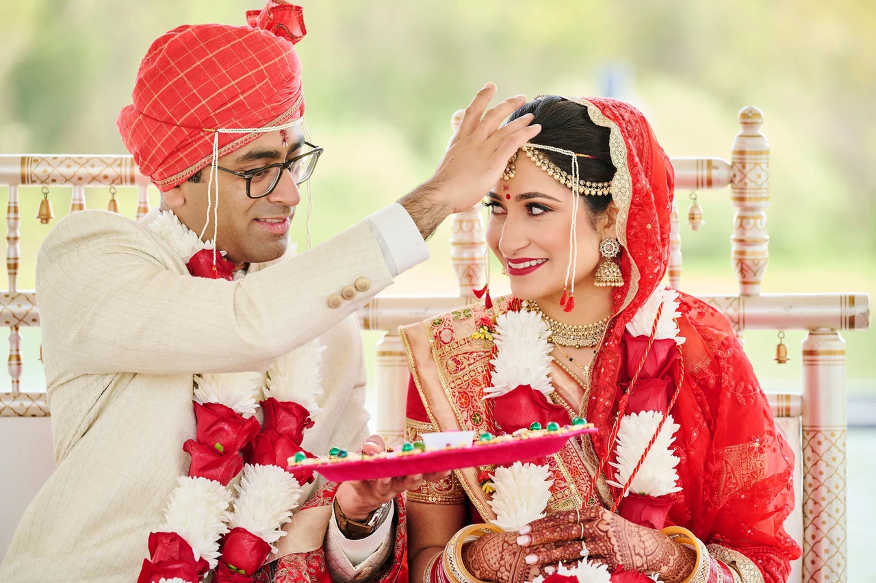 Sonal smiling toward Sushant as he applies sindoor during their wedding ceremony at Narmada Winery